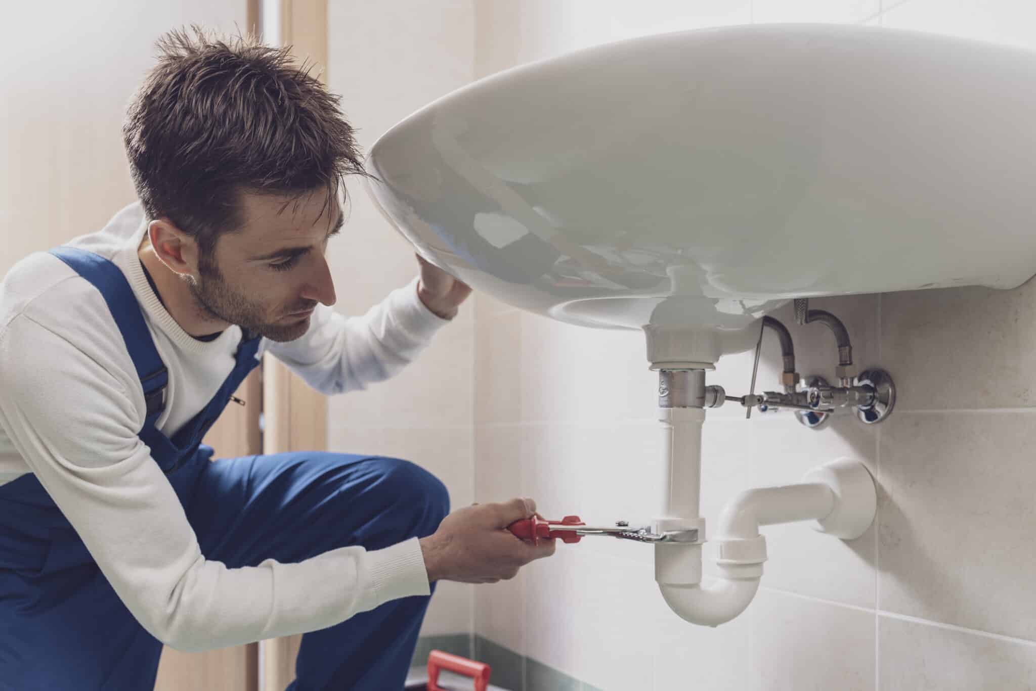Professional plumber installing or fixing a sink at home, Choosing a Plumber.