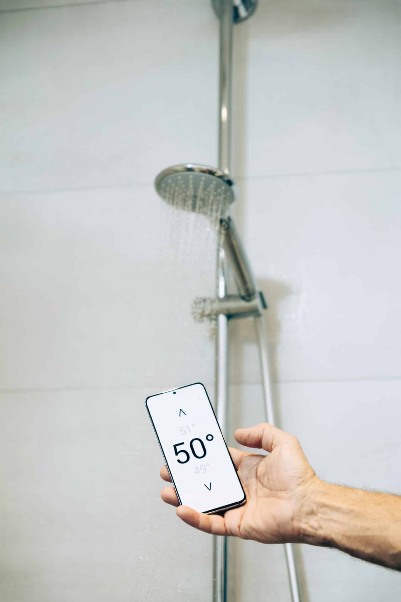 How Technology Improves Plumbing System Lifespan 2 Smart home concept: man controlling warm water temperature using app on his phone, Plumbing System Lifespan.