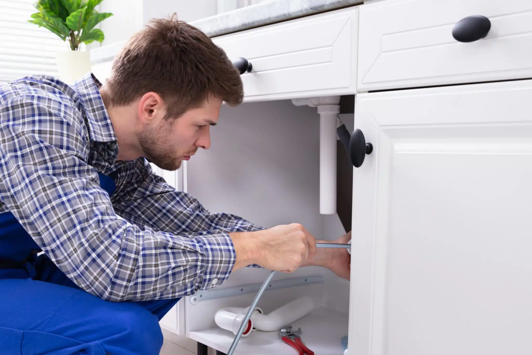 Drain Snaking vs Hydro Jetting - Knoxville Pros and Cons 2 Plumber cleaning clogged sink, Drain snaking.